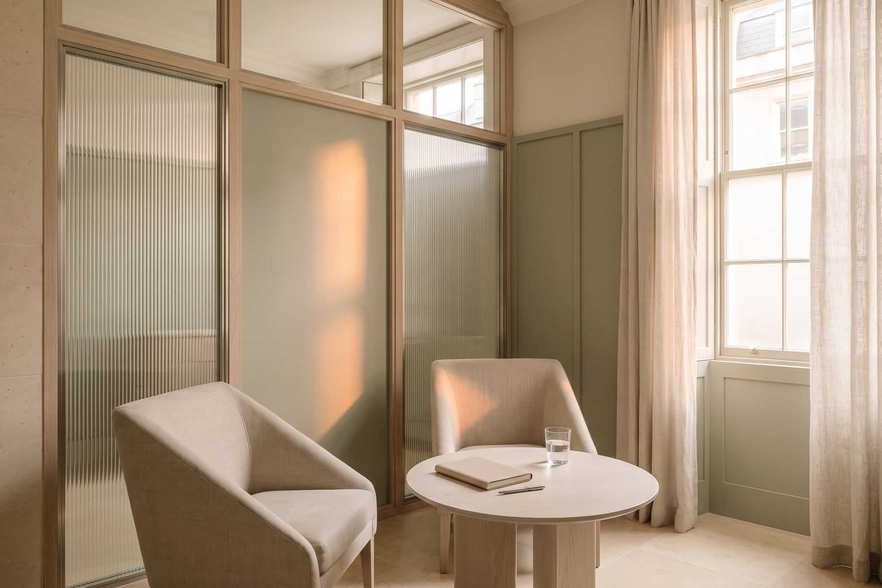 Two linen armchairs angled together in the consultation room