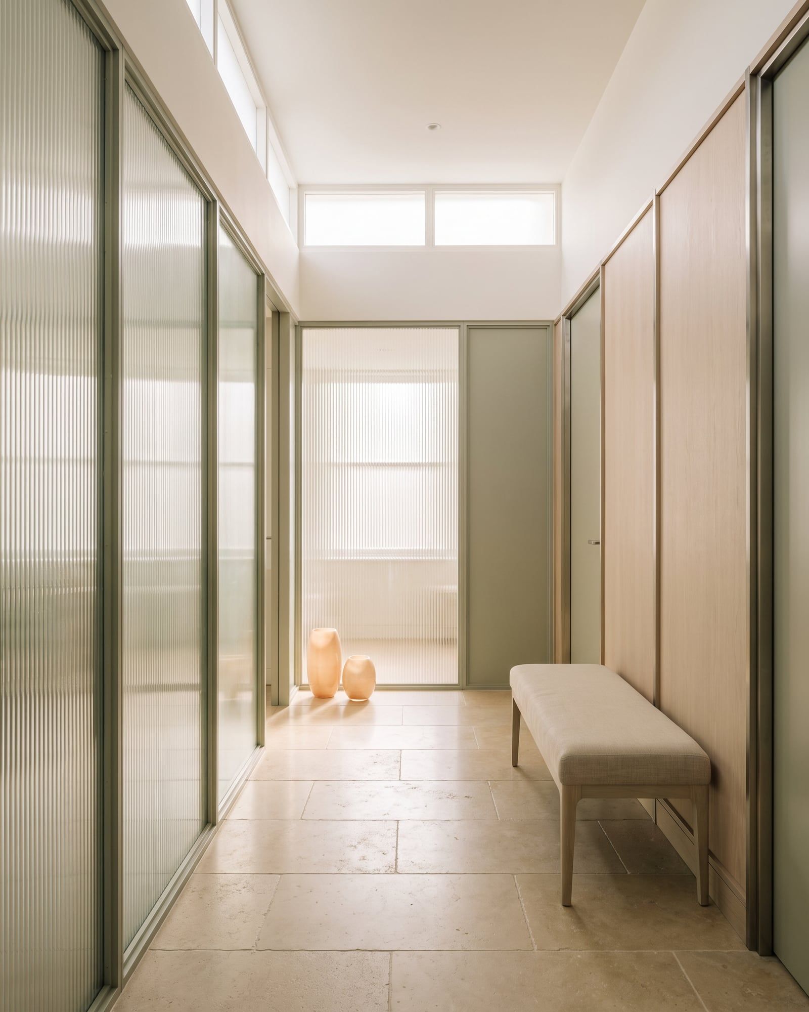 A corridor lined with reeded glass panels and a limestone floor