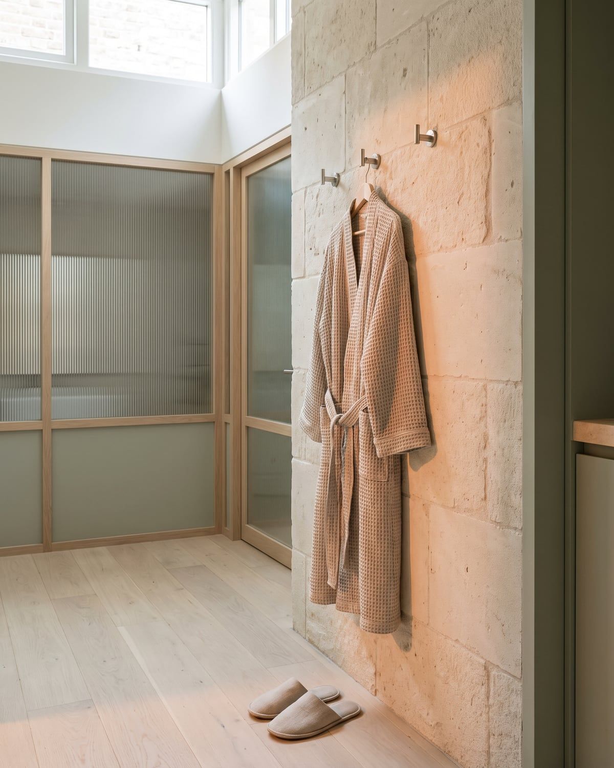 An oat robe on a nickel hook with linen slippers below